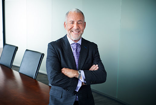 Dr. Dill smiling in a conference room with his arms folded.