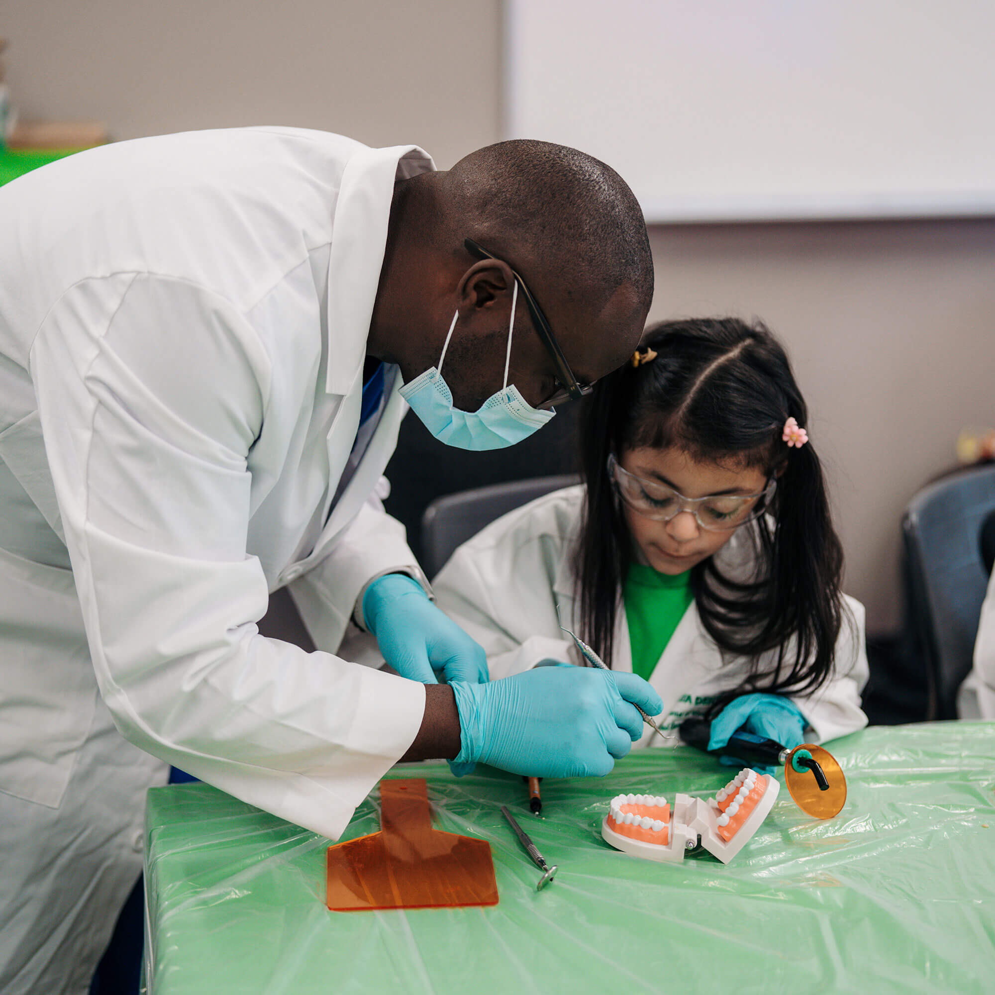 A Delta Dental professional and a child in lab coats, symbolizing the investment in future education.